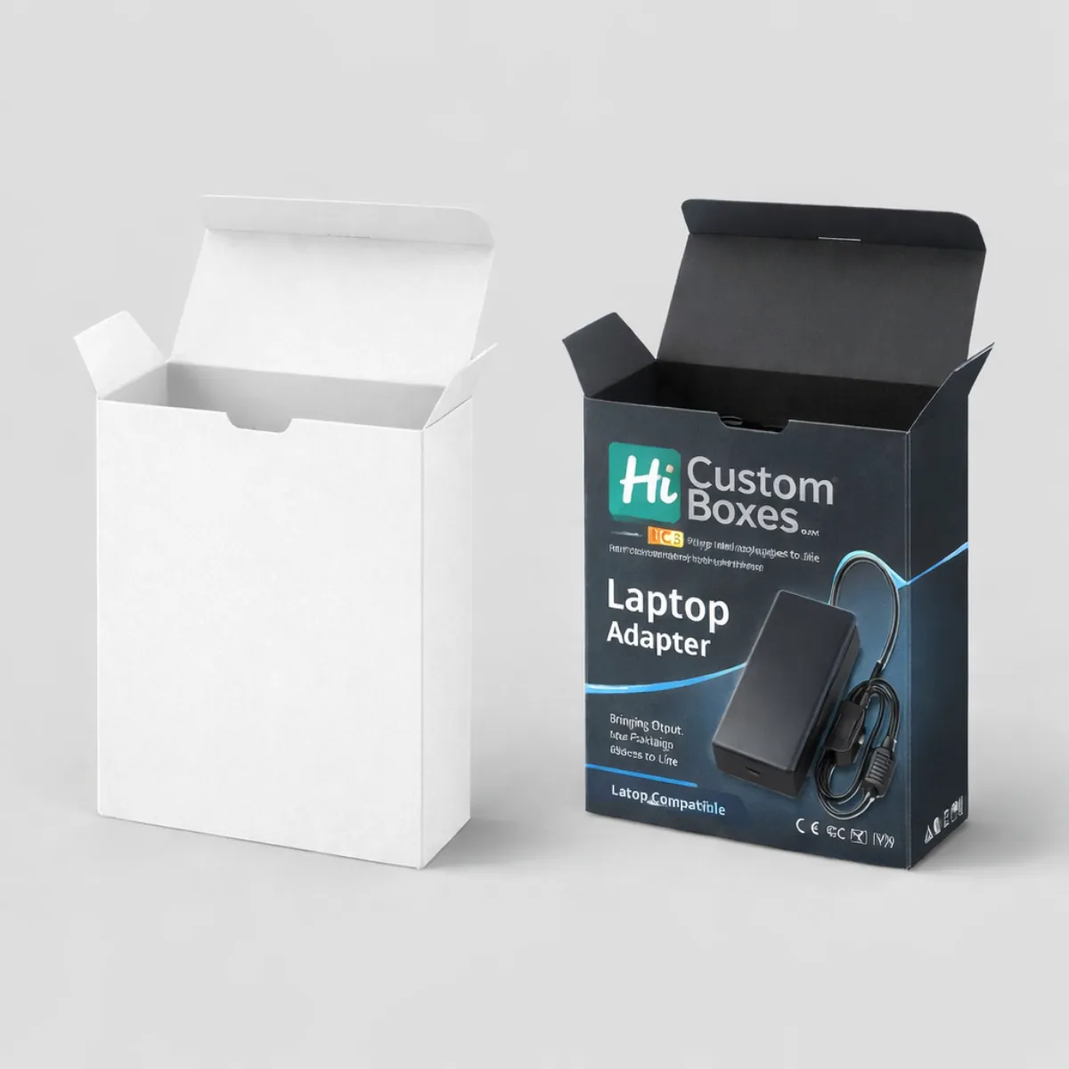 Two upright tuck-top boxes; one plain white and one dark branded version featuring a laptop adapter graphic. class=